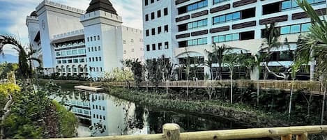A modern hotel with a central courtyard, a bridge, and a reflection pool.