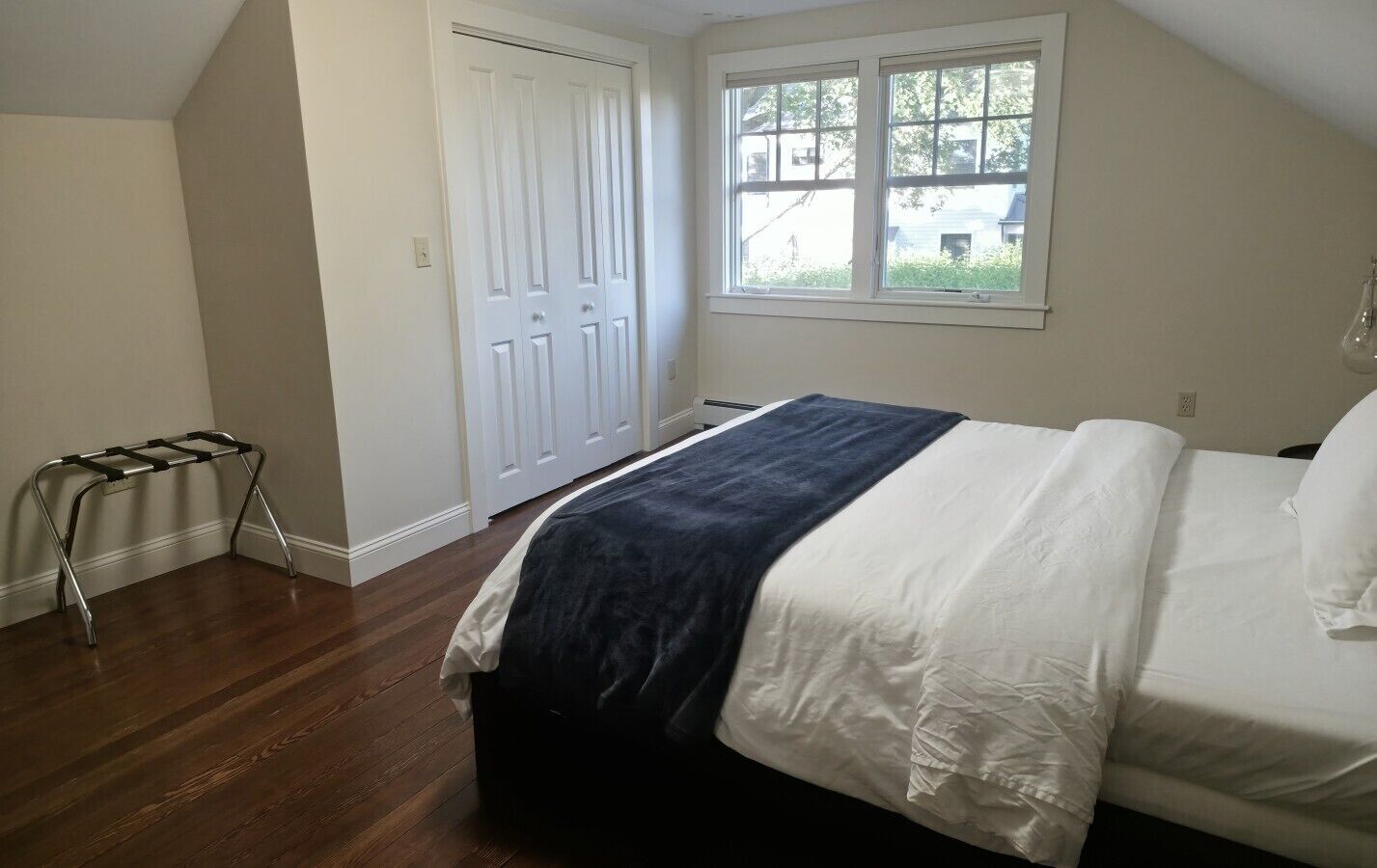 Une chambre à coucher avec un lit, une fenêtre, une porte et une chaise en métal.