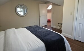 A bedroom with a bed, a door, a mirror, and a view into another room. - Middletown Bungalow w/Hot Tub and Private Yard - RIBryan Properties (Middletown)