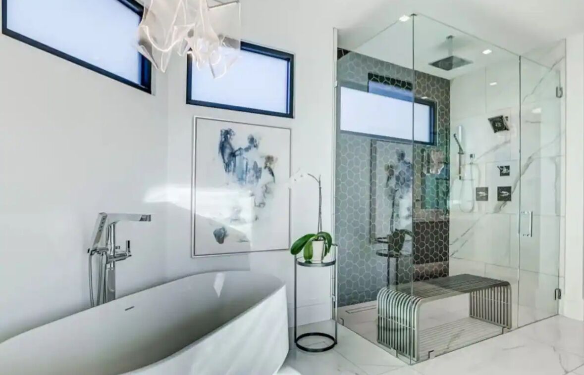 Ein modernes Badezimmer mit einer freistehenden Badewanne, einer Duschkabine aus Glas und einer kleinen Sitzbank.