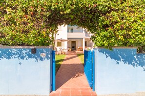 A pathway leading to a building with a blue exterior and a covered outdoor seating area.