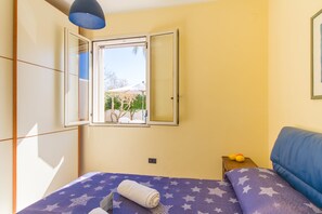 Une chambre avec un lit, une fenêtre, une table de chevet et un canapé bleu.