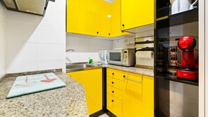 A kitchen with yellow cabinets, a microwave, a red coffee maker, and a granite countertop. - WELCS APARTAMENTO 126 PDA cerca del puerto (Platja d´Aro)