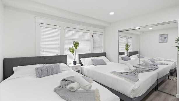 A modern hotel room with two beds, white bedding, grey headboards, and a large mirror. - 1 Mile to the Beach, Games, Remodeled 3BD Home, Fire Pit, Patio (Long Beach)
