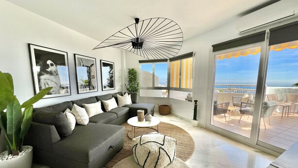 A modern living room with a grey sectional sofa, a round coffee table, and a large window offering a view of the sea. - 17 - sea view Apt. in Calahonda (Mijas Costa)