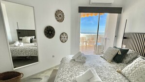 A bedroom with a bed, a mirror, and a view of the beach. - 17 - sea view Apt. in Calahonda (Mijas Costa)