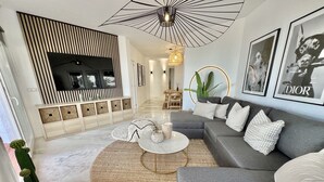 A modern living room with a grey sofa, a round coffee table, and a TV mounted on a wall. - 17 - sea view Apt. in Calahonda (Mijas Costa)