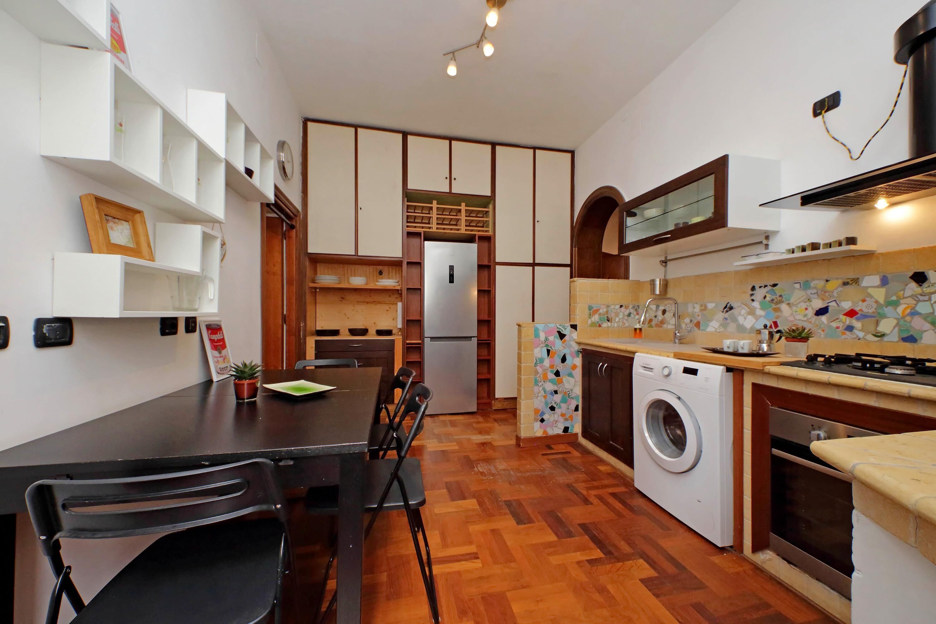 Une cuisine compacte équipée d’un lave-linge, d’une table à manger avec des chaises et d’un réfrigérateur.