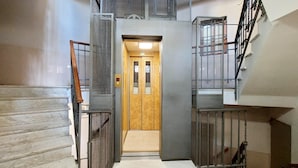A modern elevator with metal railings and a wooden door. - 4bnb - Donatello Apartment (Rome)