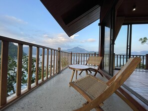 Ein Balkon mit Blick auf ein Gebirge und ein Gewässer.