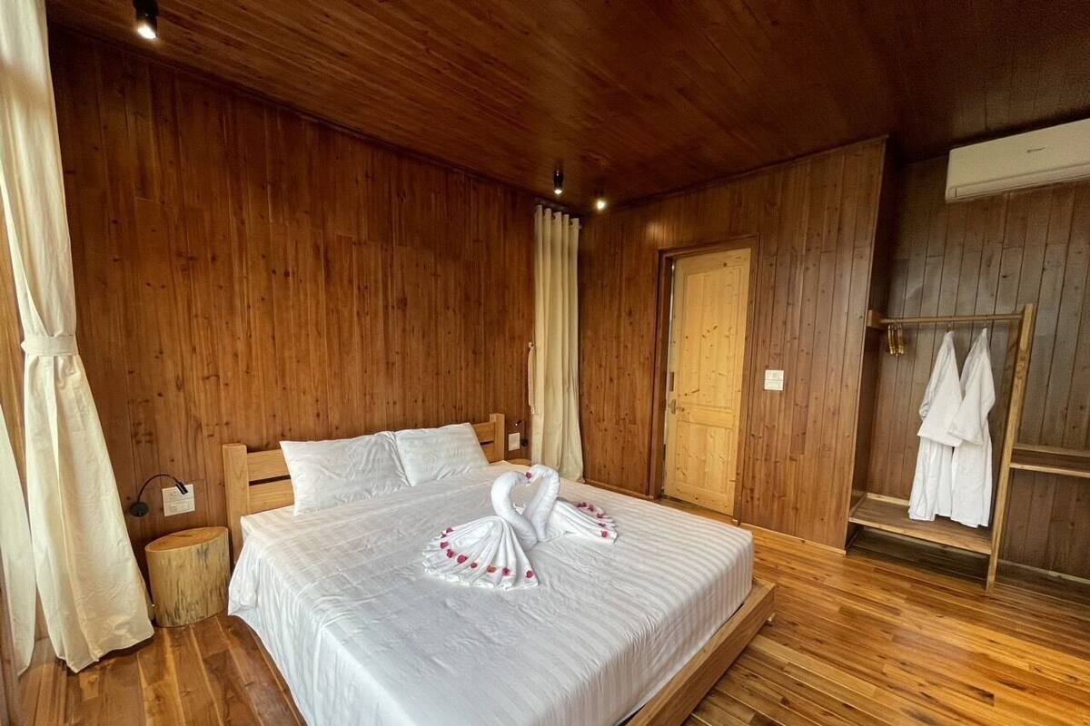 Una habitación con paneles de madera, una cama, un armario de madera y una pequeña mesa redonda.