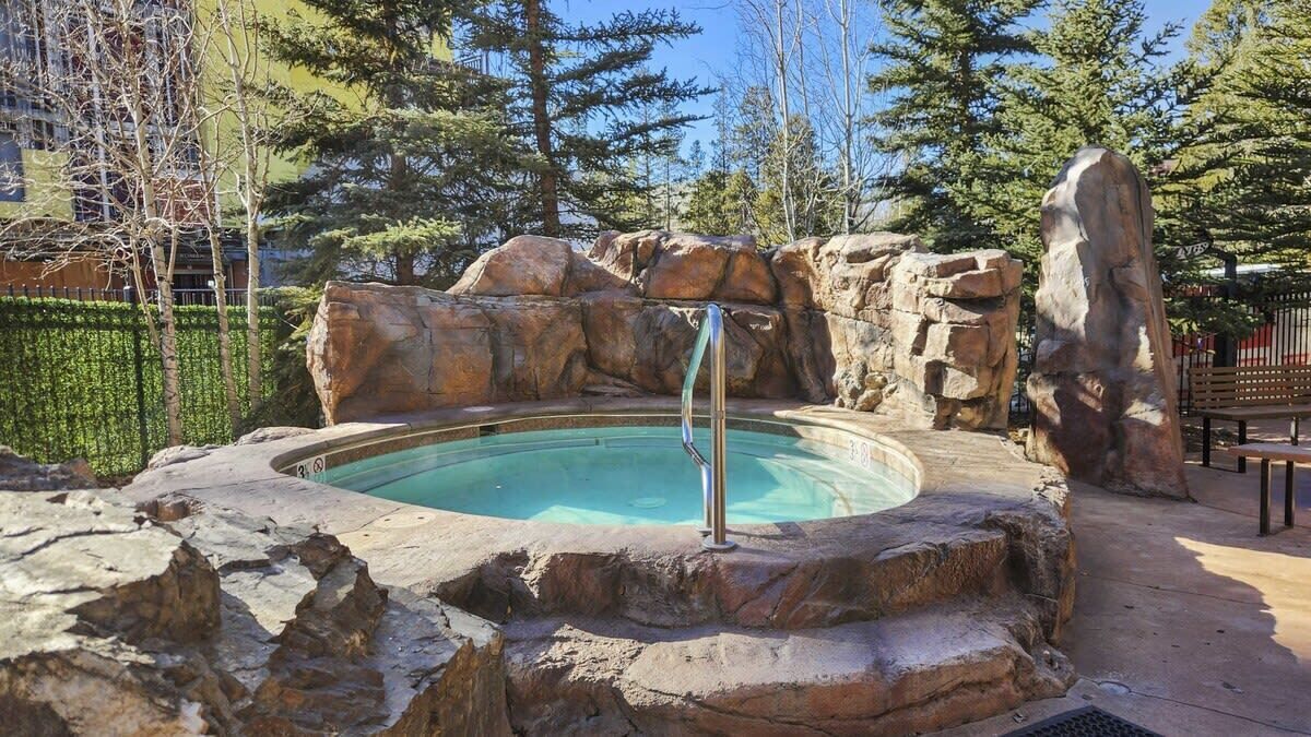 Un jacuzzi rodeado de rocas y árboles.