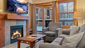Una sala de estar acogedora con chimenea, asientos cómodos, un televisor y un ventanal con vistas.
