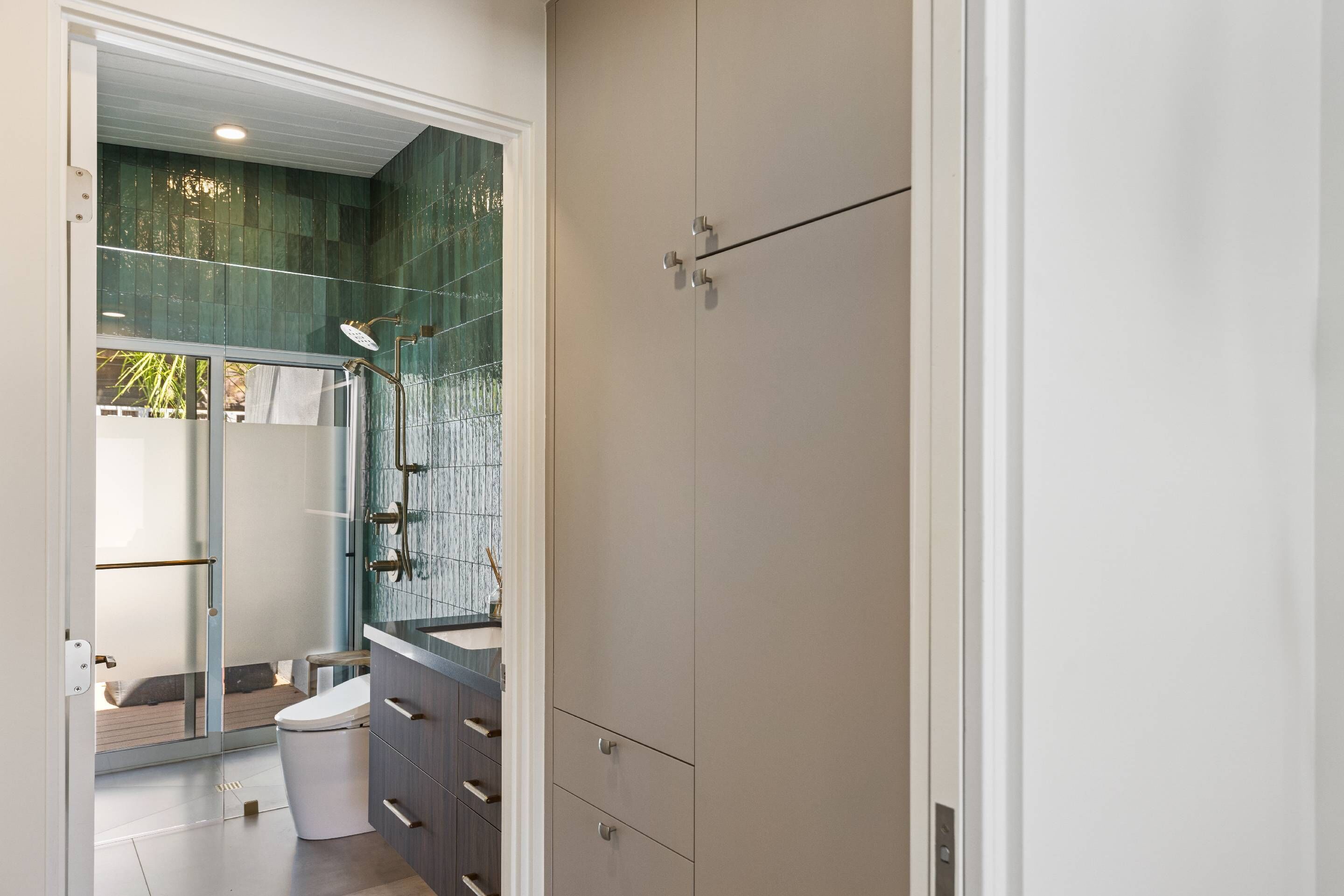 A modern bathroom with a glass shower enclosure, a white toilet, and a vanity with a mirror.