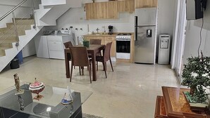 A modern kitchen with a dining area, a staircase, and a flat-screen TV mounted on the wall. - Apartment in Caracas  (Caracas)