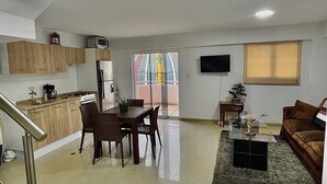 A spacious living area with a dining table, kitchen, and a TV mounted on the wall. - Apartment in Caracas  (Caracas)