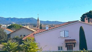 A residential area with a church tower, a pink building, and a mountain in the background.
