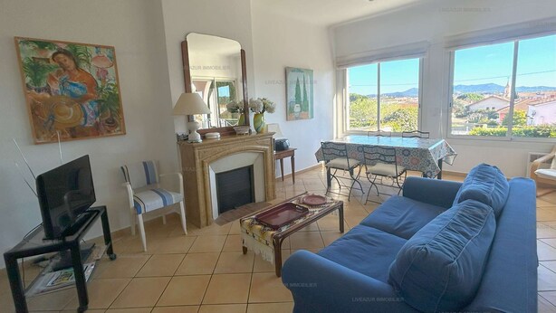 A living room with a sofa, a TV, a fireplace, and a dining area with a table and chairs.