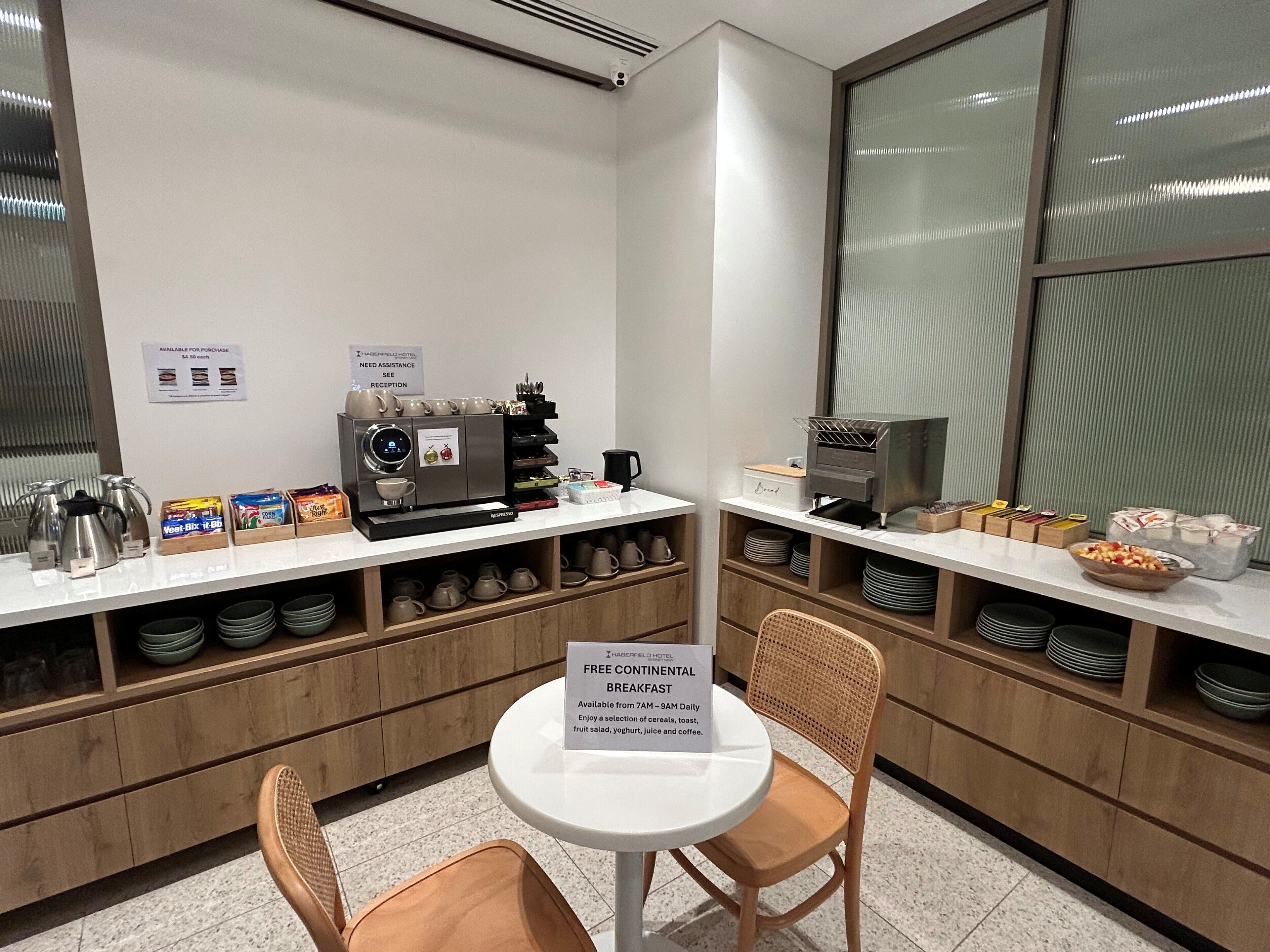 A breakfast area with a coffee machine, tea pots, and a sign for free continental breakfast.