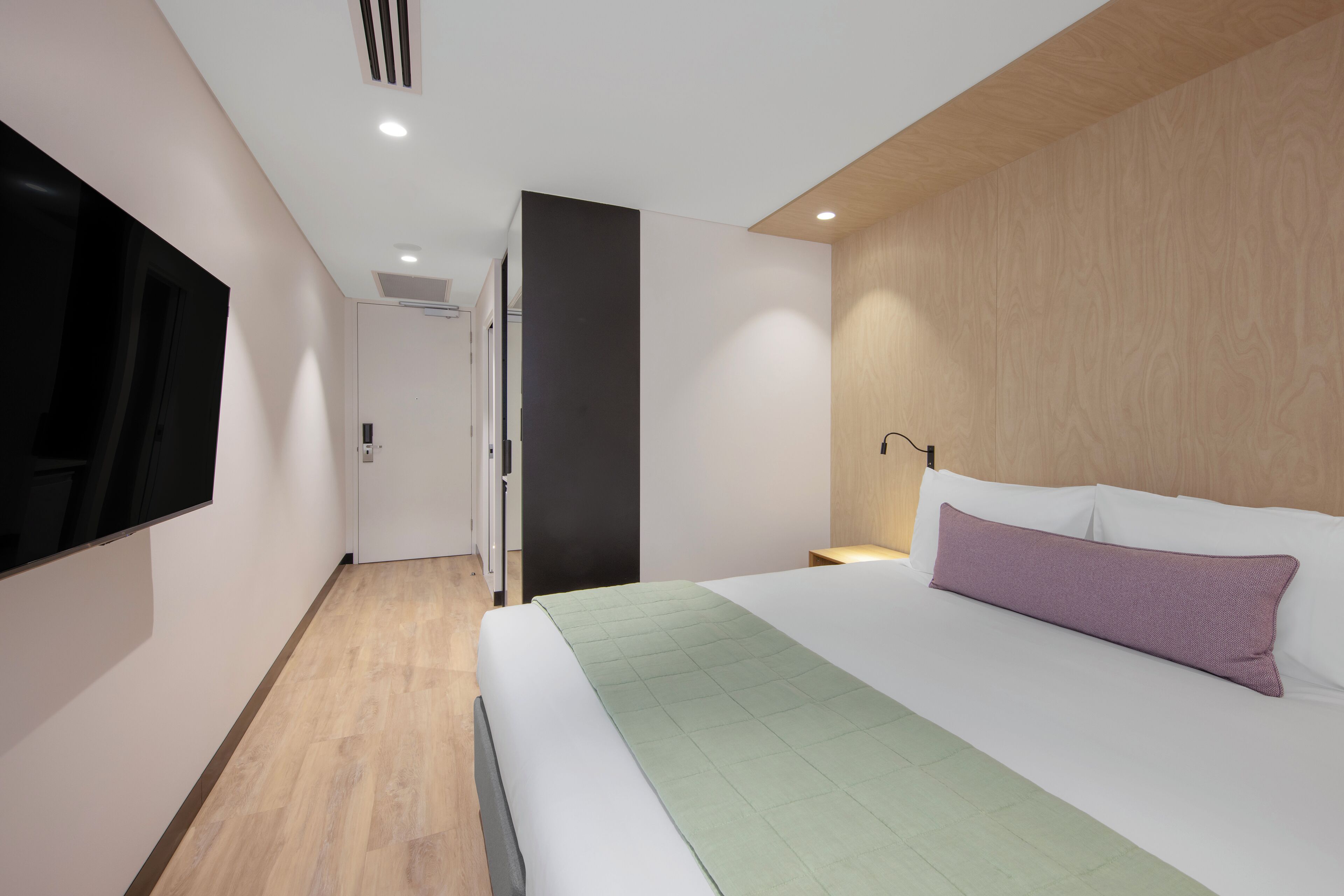 Habitació d'hotel moderna amb llit, televisió de pantalla plana i una paret decorativa de fusta.