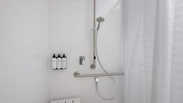 Un baño moderno con cabina de ducha, barra de apoyo y toallero con botellas.