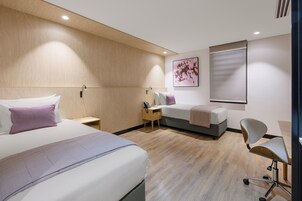 A modern hotel room with two beds, a desk, and a chair.