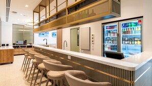 Eine moderne Bar mit einer Theke, Barhocker und einem mit Getränken gefüllten Kühlschrank.
