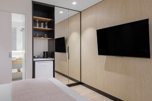 A modern hotel room with a bed, a flat-screen TV mounted on the wall, a built-in wardrobe, and a small kitchenette area. - Haberfield Hotel (Haberfield)