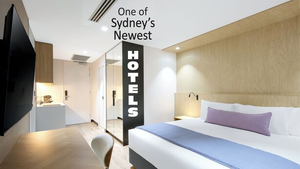 A modern hotel room with a bed, bedside table, and a TV. - Haberfield Hotel (Haberfield)