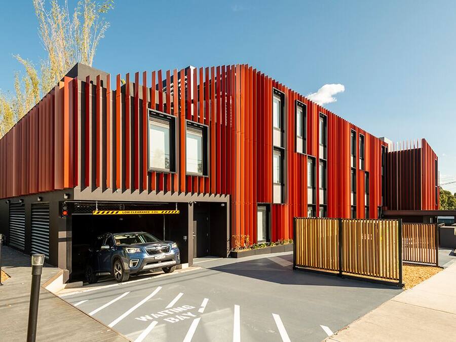 A modern building with a garage entrance, a car parked inside, and a clear sky.