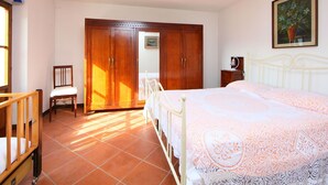 A bedroom with a bed, a chair, a wardrobe, and a painting on the wall.