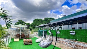 A patio with artificial grass, a hanging chair, and outdoor seating. - Jardin Colonial Boutique Hotel (Santo Domingo)
