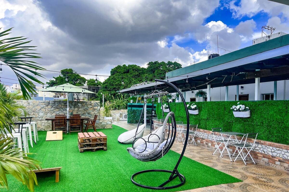 A patio with artificial grass, a hanging chair, and outdoor seating.