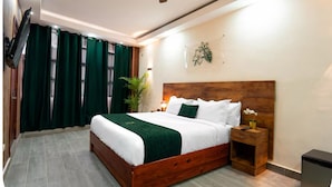 A neatly arranged bedroom with a wooden bed, green curtains, a ceiling fan, and a small bedside table with a lamp. - Jardin Colonial Boutique Hotel (Santo Domingo)