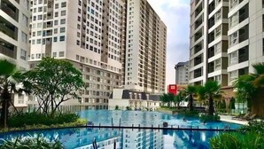 A swimming pool surrounded by high-rise residential buildings, with palm trees and a clear sky. - Golden Mansion Apartments Phu Nhuan (Ho Chi Minh City)