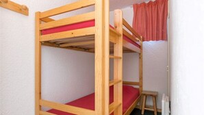 A bunk bed with red bedding in a room with white walls and a small stool. - Studio 4 ppl, balcony, near the ski station (Les Deux Alpes)