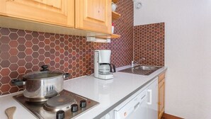 A kitchen with a stove, coffee maker, and a sink. - Studio 4 ppl, balcony, near the ski station (Les Deux Alpes)