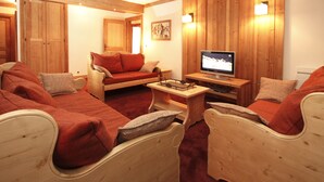 Ett mysigt rum med träväggar, en soffa, en fåtölj, ett litet bord och en tv.