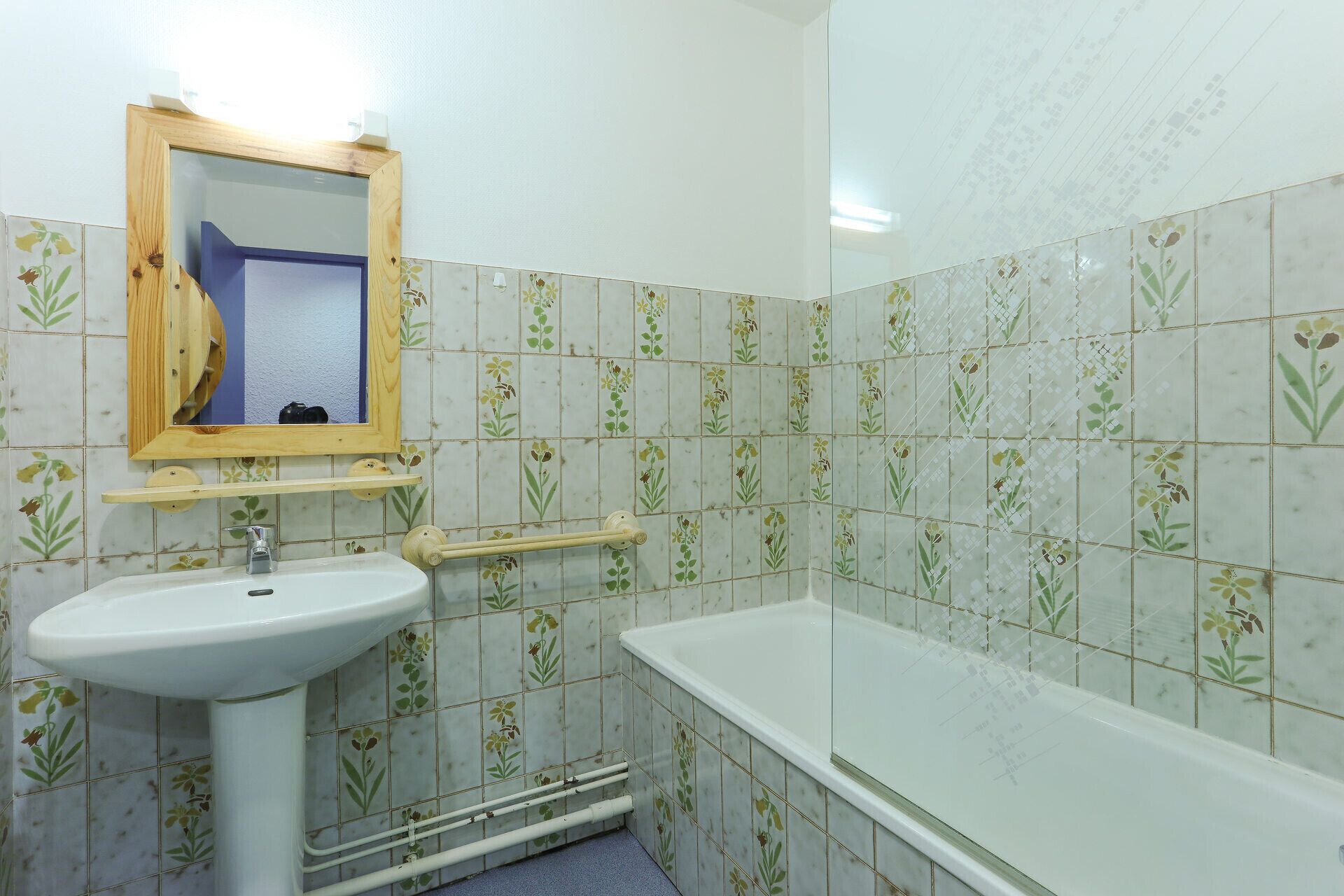 A bathroom with a sink, mirror, and bathtub.