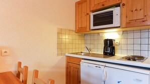 A compact kitchen with wooden cabinets, a microwave, a coffee maker, and a dishwasher. - Studio 4 ppl, splendid view from balcony (Les Deux Alpes)