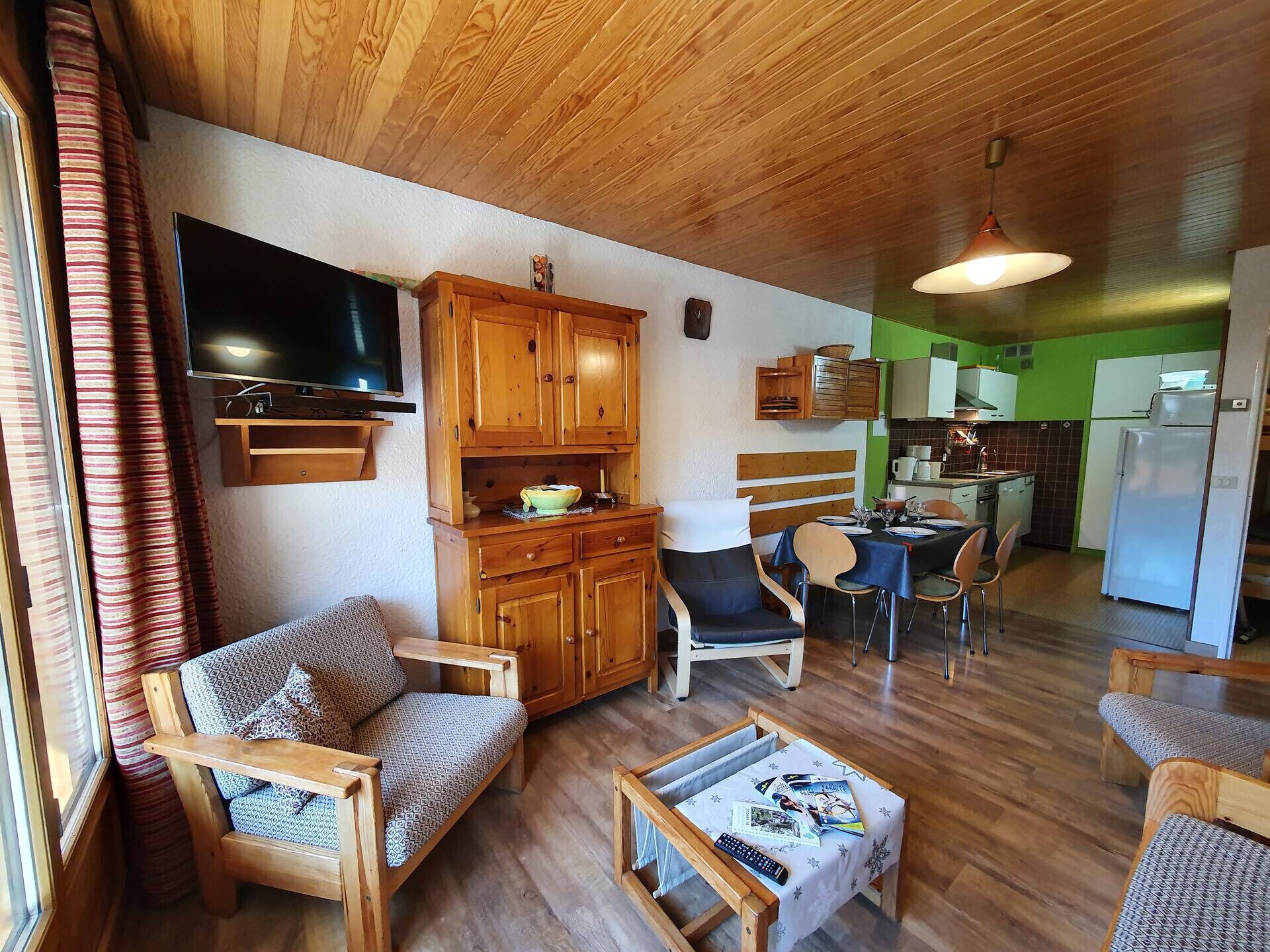 A cozy living room with wooden furniture, a television, and a dining area with a table and chairs.