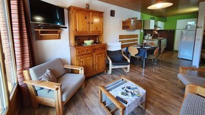 Een gezellige woonkamer met houten meubels, een televisie en een eethoek met een tafel en stoelen.