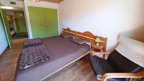 Een slaapkamer met een houten bed, een groene deur en een houten plafond.