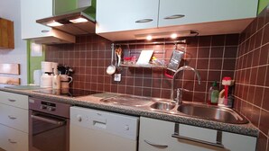 Een moderne keuken met witte kasten, een roestvrijstalen spoelbak en een afzuigkap.