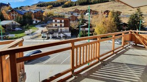 A balcony with a view of a town, including buildings and a parking area.