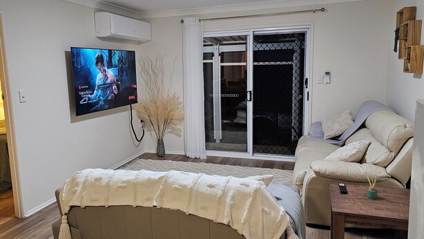 Una sala de estar con televisión de pantalla plana, un sofá, una mesa de centro y un ventanal corredizo que da a un balcón.