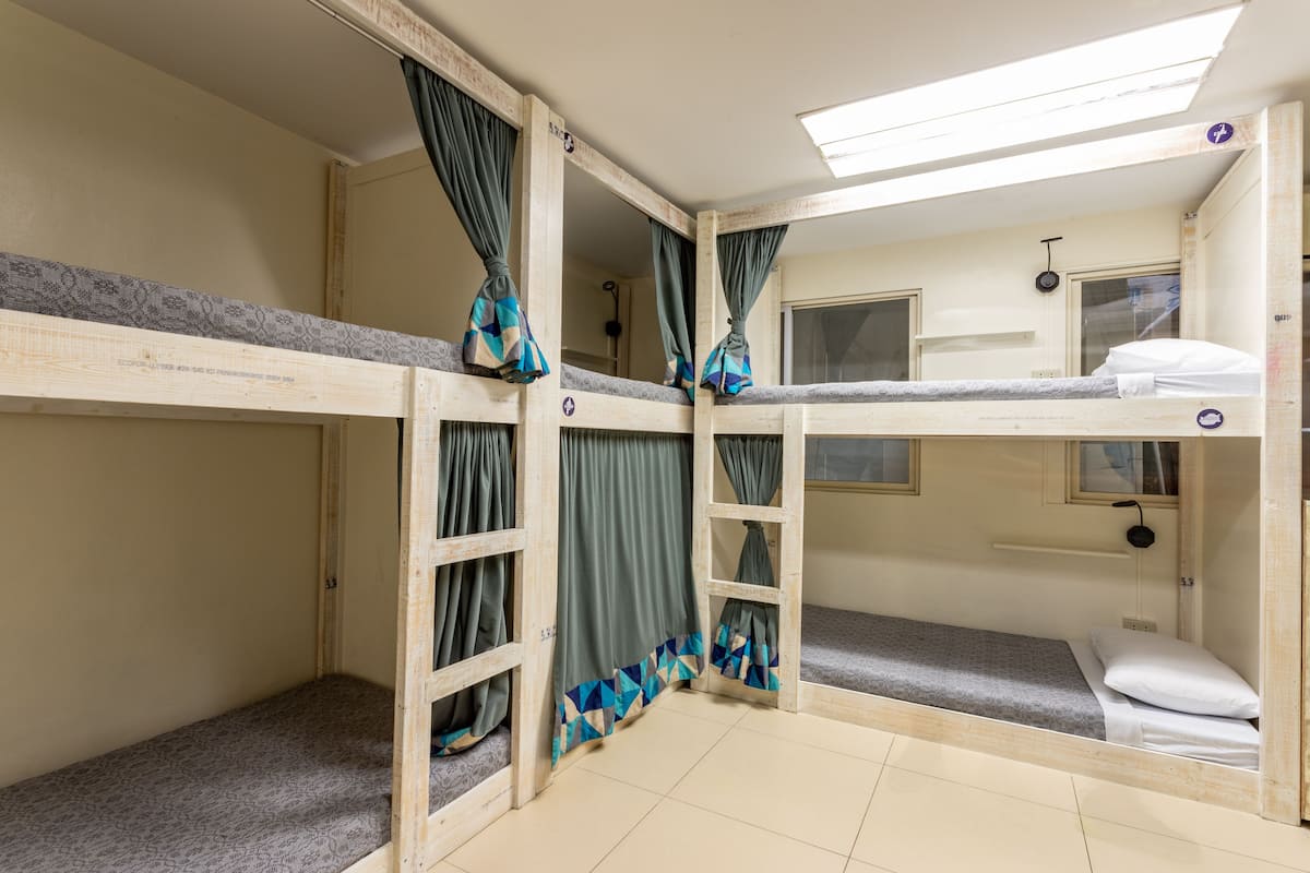 A bunk room with three bunk beds, each with curtains and a window.