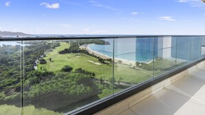 A balcony with a clear view of a golf course, beach, and ocean. - B-1702 Stunning ocean view 2 bedroom (Cupecoy)