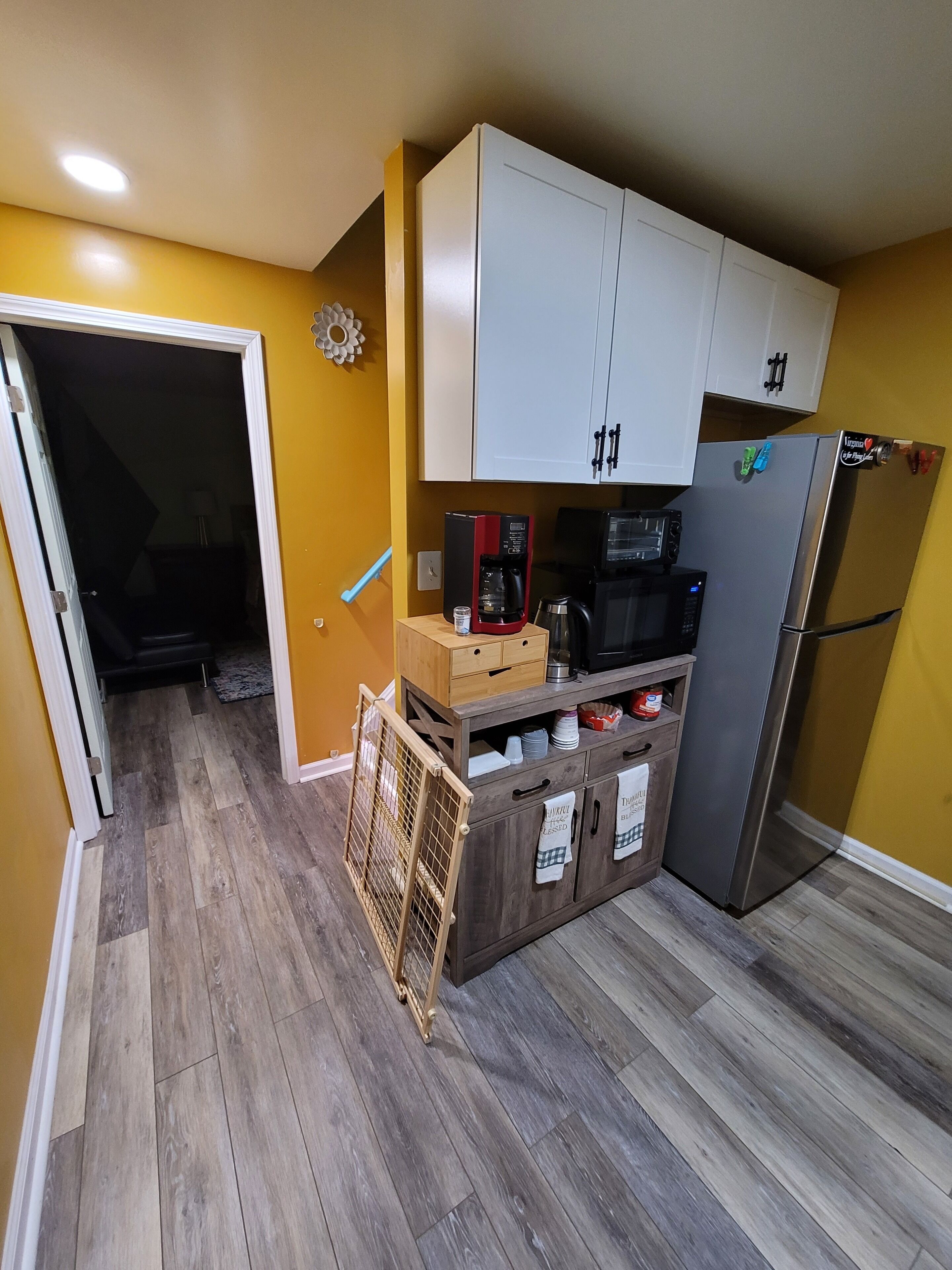 A compact kitchen with white cabinets, a stainless steel refrigerator, and a coffee maker.