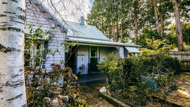 Una casa con veranda, circondata da alberi e un giardino.